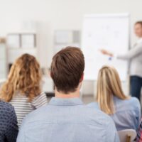 frau hält einen vortrag am flipchart vor einer gruppe frau hält einen vortrag am flipchart vor einer gruppe