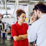 Serious cute caucasian female employee standing with arms crosse