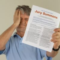 Upset man holding jury duty summons received in the mail Upset man holding jury duty summons received in the mail