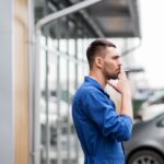 auto mechanic smoking cigarette at car workshop