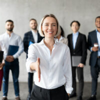 Cheerful Businesswoman Stretching Hand For Handshake Greeting To Camera Making Career Offer Standing In Modern Office. Recruitment And Employment, Human Resources, Join Our Team Concept Cheerful Businesswoman Stretching Hand For Handshake Greeting To Camera Making Career Offer Standing In Modern Office. Recruitment And Employment, Human Resources, Join Our Team Concept