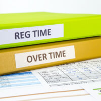 Regular time and Over time words on labels, document binders place on employee time sheets