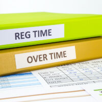 Regular time and Over time words on labels, document binders place on employee time sheets Regular time and Over time words on labels, document binders place on employee time sheets
